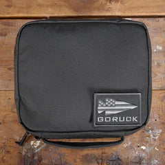 GORUCK padded field pocket in Armor Grey, displayed on wooden surface with GORUCK logo patch
