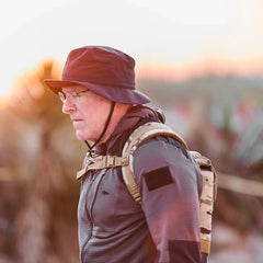Man rucking outdoors at sunrise wearing GORUCK MultiCam ruck plate carrier and bucket hat