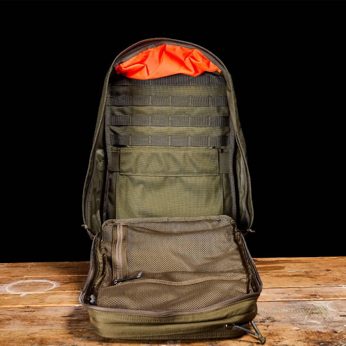 GORUCK Ranger Green rucksack open, showcasing interior compartments on wooden table