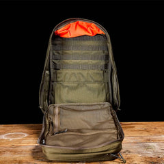GORUCK Ranger Green rucksack open, showcasing interior compartments on wooden table