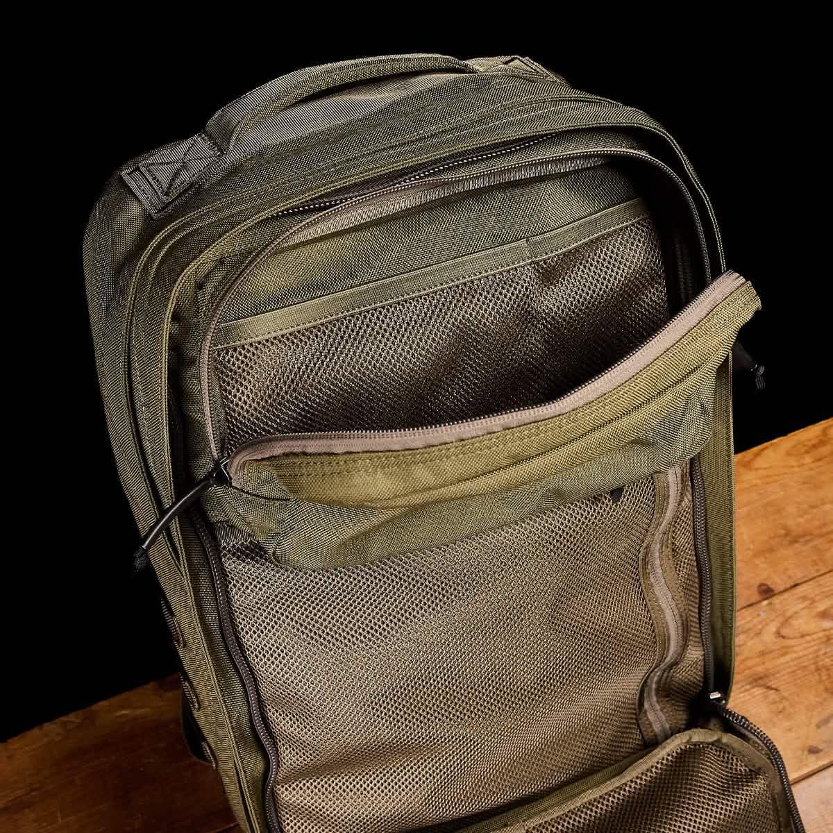 GORUCK Ranger Green tactical backpack open to show mesh interior pockets on wood surface