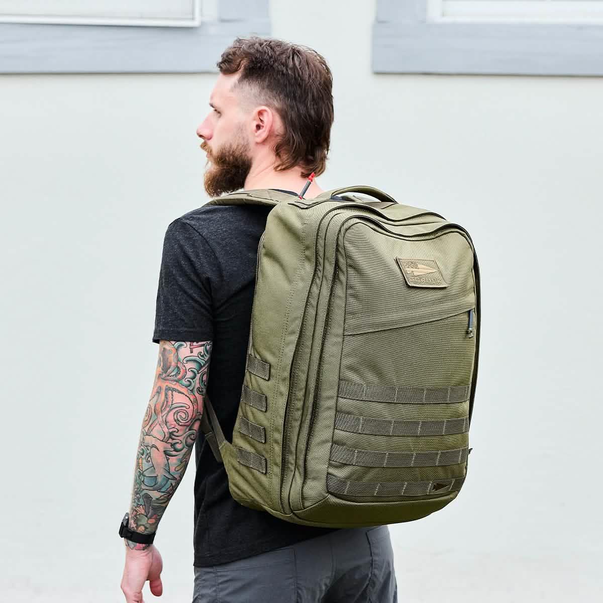 Man wearing large Ranger Green GORUCK backpack, outdoor urban setting, durable rucking gear