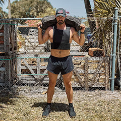 Man in GORUCK black Ranger Panties shorts, weighted vest, and cap, rucking outdoors.