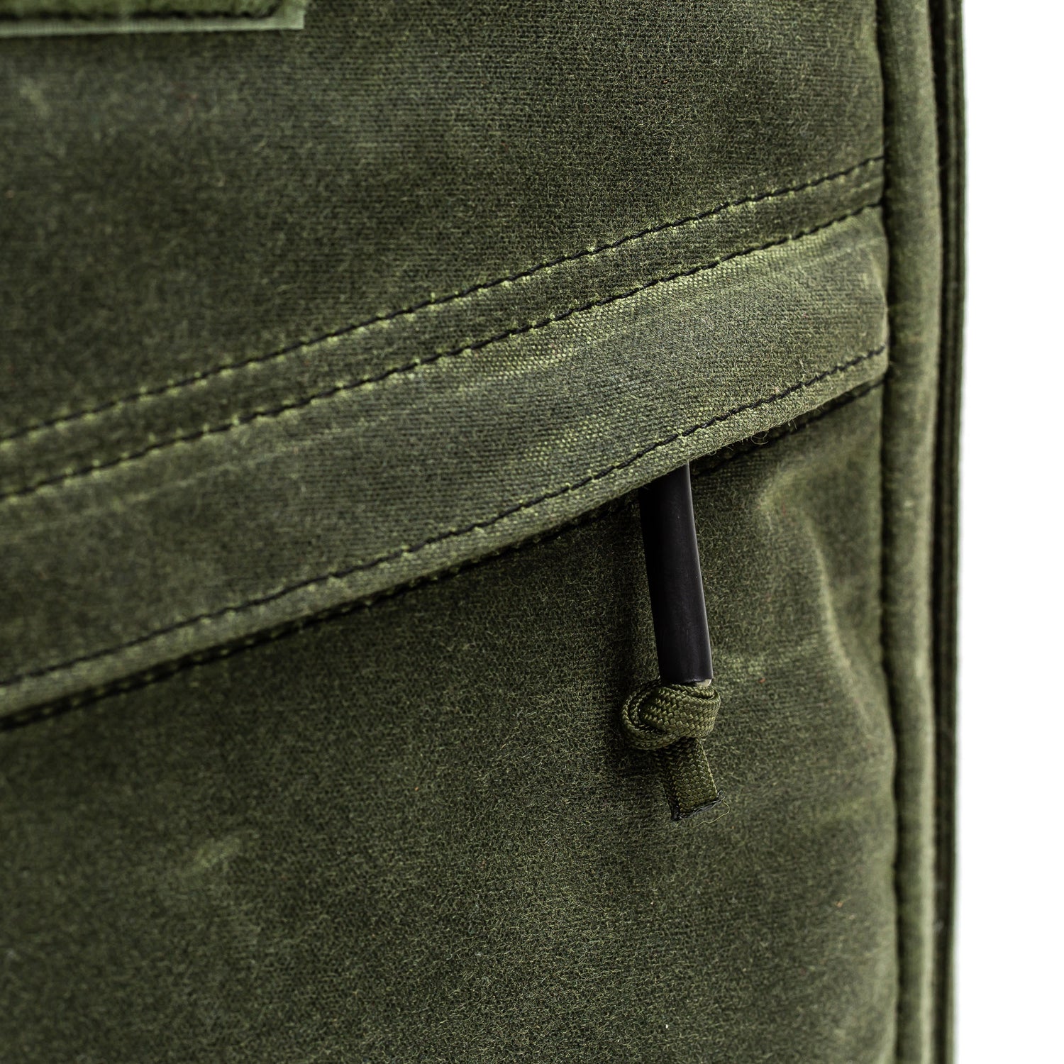 Close-up of a green fabric pocket with black zipper pull and visible stitching on the GR1 USA - Heritage Waxed Canvas backpack.