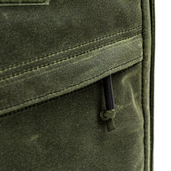 Close-up of a green fabric pocket with black zipper pull and visible stitching on the GR1 USA - Heritage Waxed Canvas backpack.