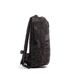 Side view of the Rucker 5.0, a black camouflage rucksack with multiple straps and handle, designed for rucking and enhanced lumbar support, standing upright on a white background.
