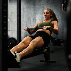 Woman wearing GORUCK Tough Flex Ranger Green sports bra rowing on exercise machine in gym