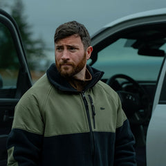 Man in GORUCK jacket standing outdoors by open car door, rugged and ready for adventure