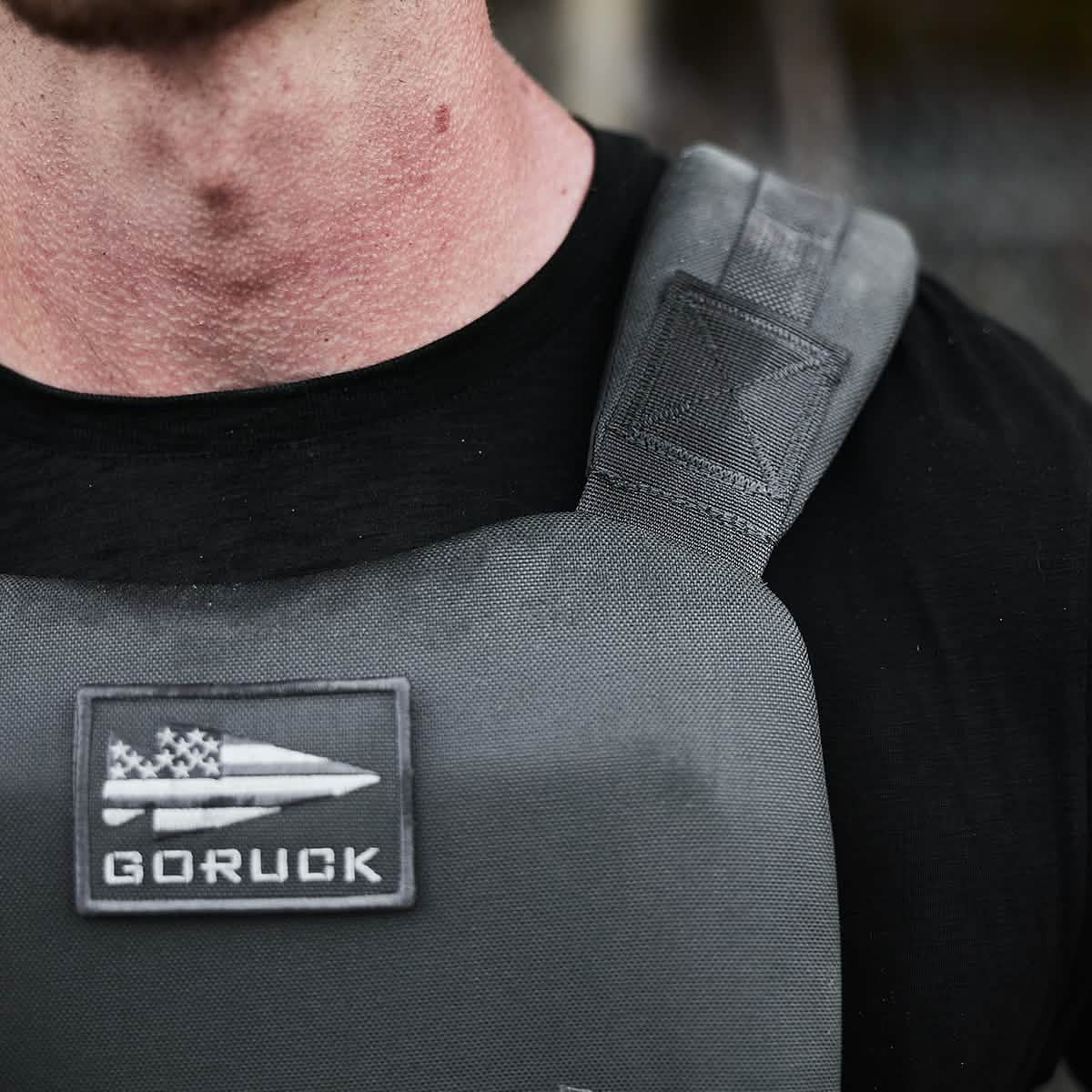Close-up of a person wearing a black shirt and the Training Weight Vest 2.0 in gray, featuring a 