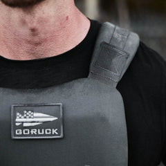 Close-up of a person wearing a black shirt and the Training Weight Vest 2.0 in gray, featuring a "GORUCK" patch on the front.