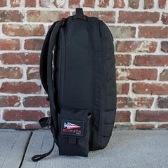 GORUCK black rucksack with side pocket attachment on concrete, brick wall background