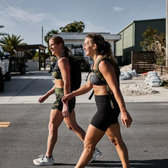 Two women rucking outdoors with GORUCK backpacks in athletic gear on a sunny street