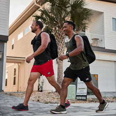 Two men rucking with GORUCK gear and backpacks outside modern homes on a sunny day
