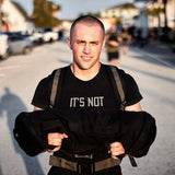 Teen boy rucking outdoors with GORUCK gear, carrying a weighted sandbag, strength training