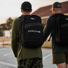 Two men wearing GORUCK backpacks and rucking gear walking outdoors at sunset