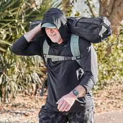 Man wearing black GORUCK ToughMesh hoodie rucking with weighted sandbag outdoors