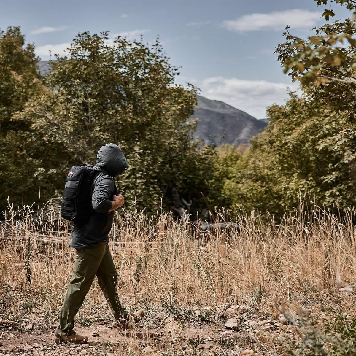 Man hiking outdoors in a GORUCK ToughMesh hoodie and backpack in nature trail setting