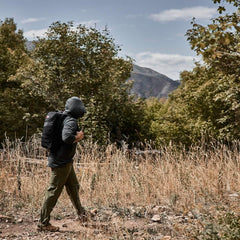 Man hiking outdoors in a GORUCK ToughMesh hoodie and backpack in nature trail setting