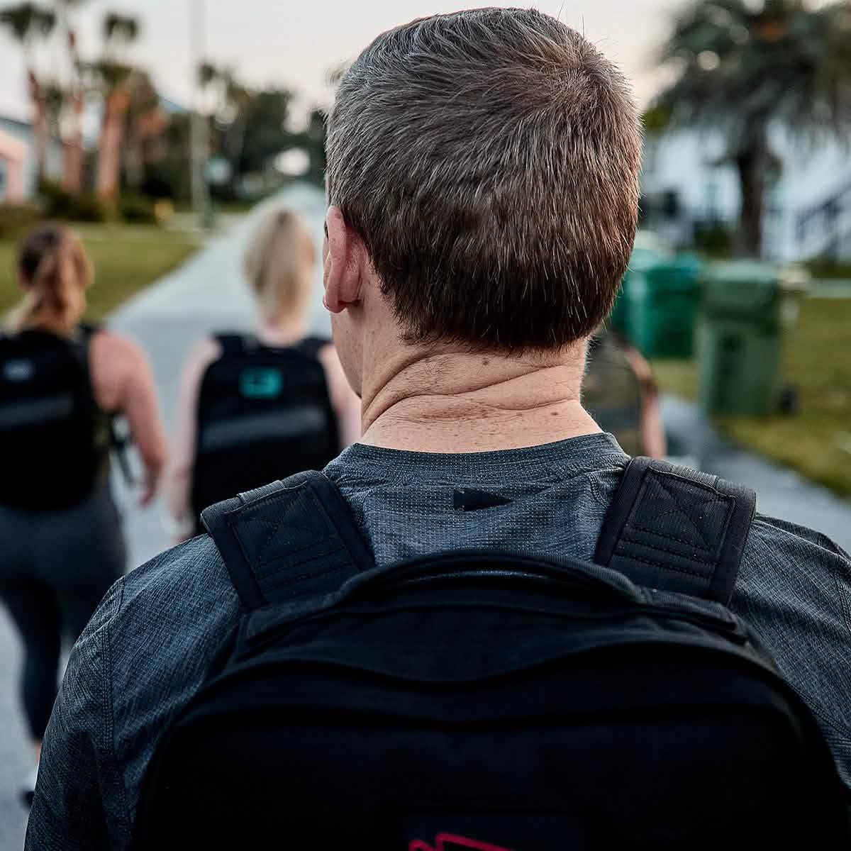 Group rucking with GORUCK backpacks on a suburban street, teamwork fitness activity