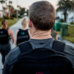 Group rucking with GORUCK backpacks on a suburban street, teamwork fitness activity
