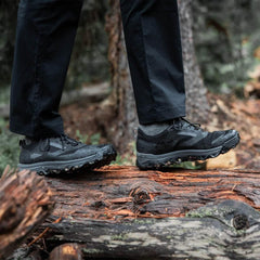 GORUCK Trail Merino Sock Charcoal worn with black trail shoes, outdoors on a log in forest