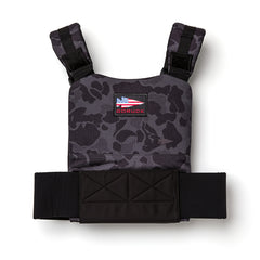 The Training Weight Vest 2.0 features a black and grey camo design, wide adjustable straps, a GORUCK patch, and is built to securely hold ruck plates for intense training sessions.