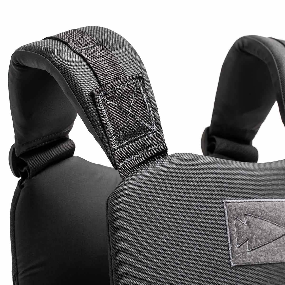 Close-up of padded black backpack shoulder straps attached to a textured fabric back panel, offering durability similar to the Training Weight Vest 2.0.