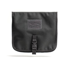 The Wire Dopp is a black rectangular EDC essentials pouch with a buckle closure and front patch, ideal as a rugged tech accessory bag, shown here against a white background.