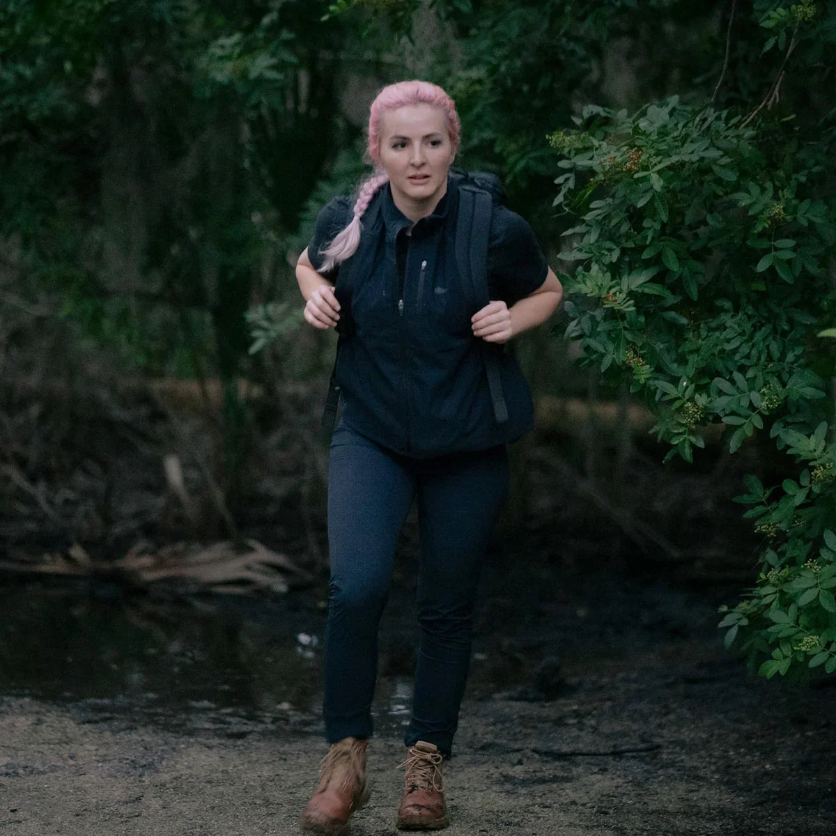 Woman wearing GORUCK black Tough Dry fleece vest, hiking outdoors with backpack in forest