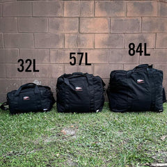 Three GORUCK rucking bags in 32L, 57L, and 84L sizes displayed outdoors against a brick wall.