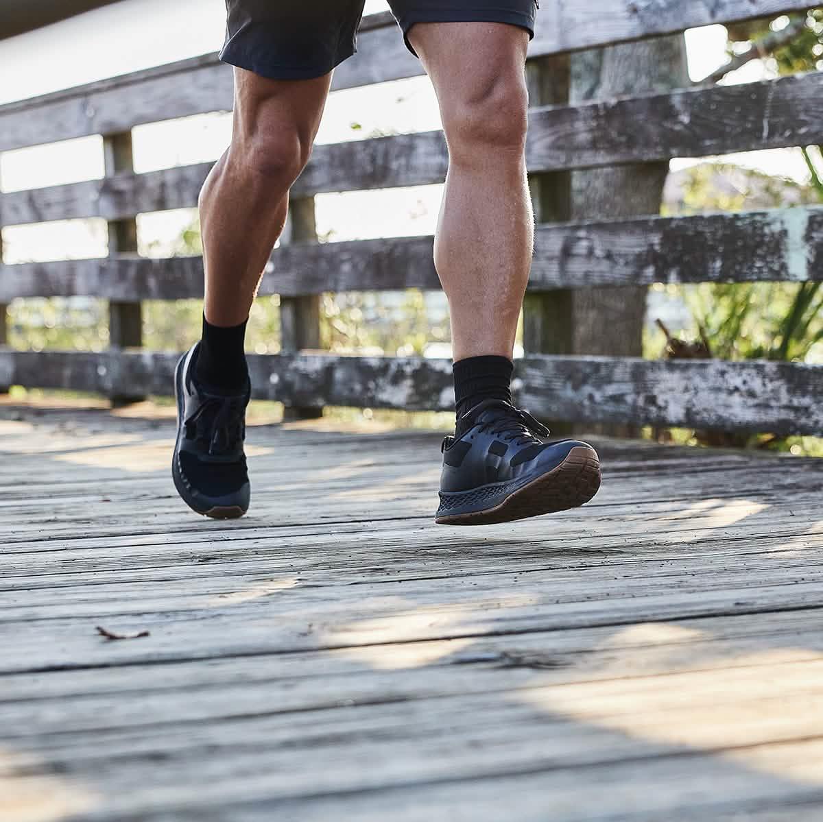 Man wearing GORUCK black rucking shoes running on a wooden outdoor trail