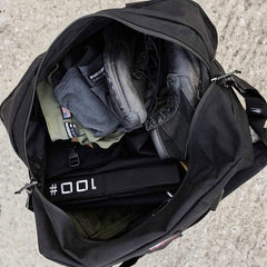 GORUCK rucking gear in open black duffel, including boots, apparel, and weight plate