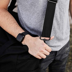 Man in grey shirt holding GORUCK rucking gear bag with sturdy black strap outdoors