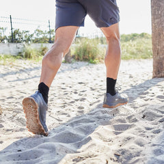 Man running on sand in GORUCK rucking shoes and shorts outdoors