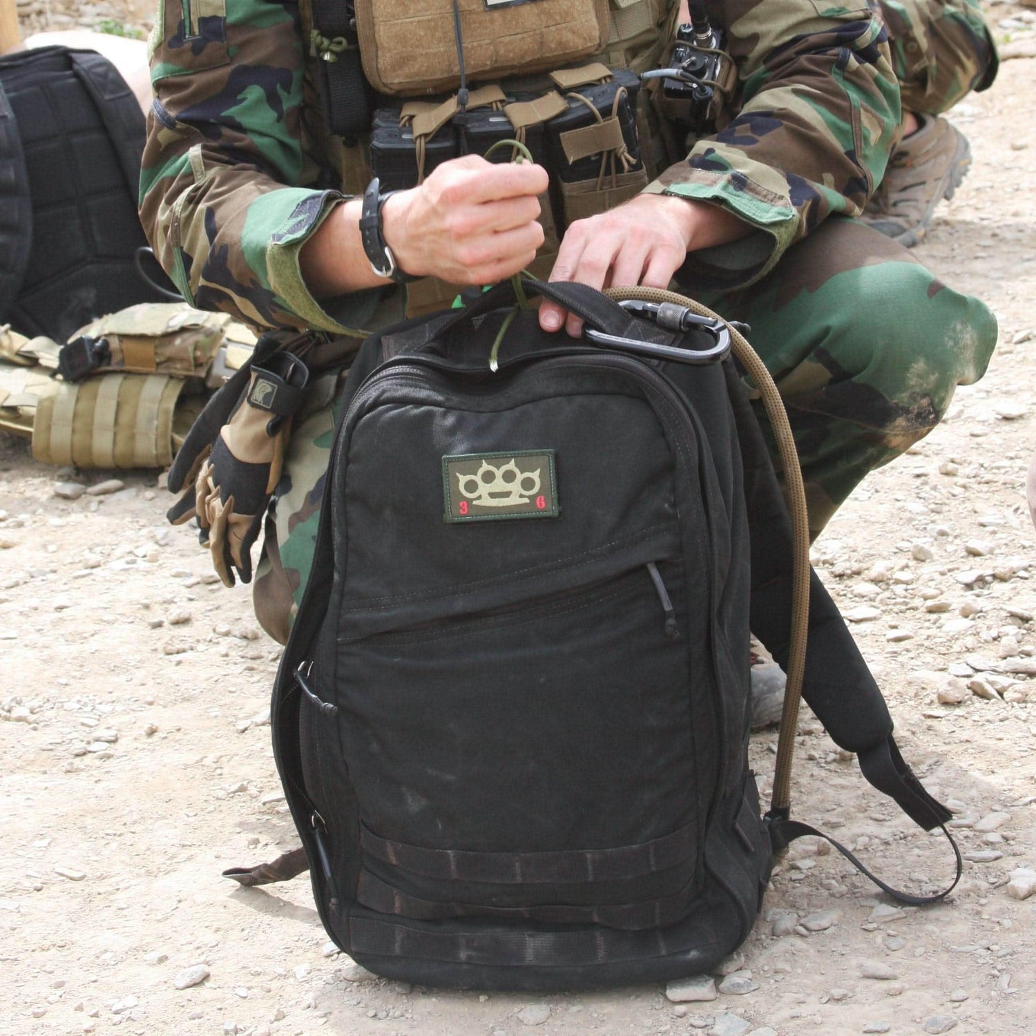 GORUCK rucksack with tactical patch, handled by person in camouflage gear outdoors