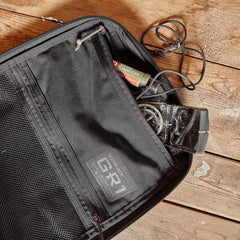 GORUCK GR1 rucksack interior with compass, lip balm, and cord on a wooden surface