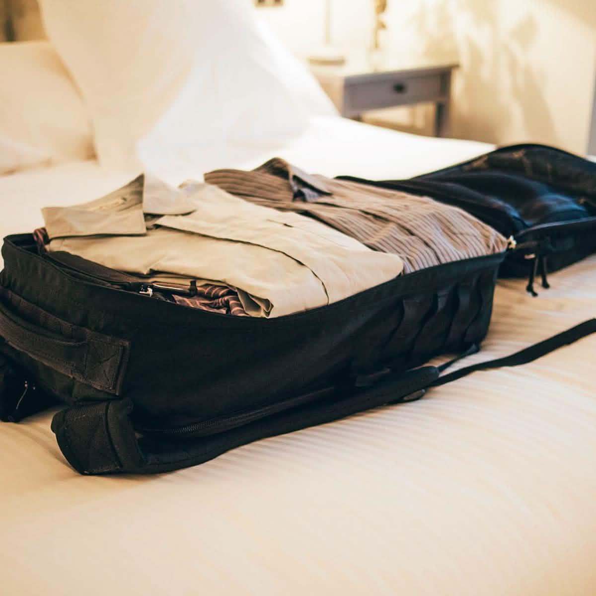 GORUCK rucksack open flat on bed, packed with neatly folded clothes, travel gear