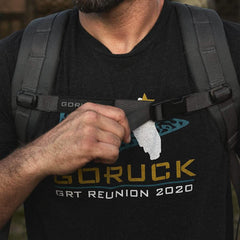 Man wearing GORUCK backpack and GRT Reunion 2020 t-shirt fastening chest strap outdoors