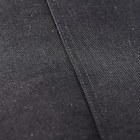 Close-up of black textured fabric with a visible seam running diagonally across the surface.