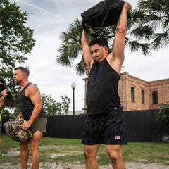 Men in black performance tank tops lifting weighted bags outdoors, GORUCK rucking gear