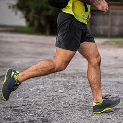 Man running outdoors in GORUCK athletic shorts and black sneakers with neon soles