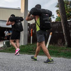 Men rucking outdoors with GORUCK backpacks and sandbags, athletic training gear visible