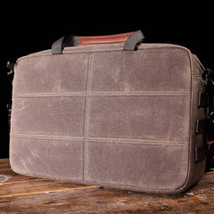 GORUCK rugged brown canvas laptop bag with leather handle on rustic wood table