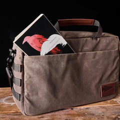 GORUCK brown canvas bag on wood table with book in front pocket, rugged rucking gear