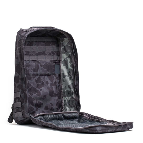 The GR1 rucksack, shown in black camo with the front flap open to reveal its mesh pocket and organizational panels, is built in the USA to Special Forces-grade standards.