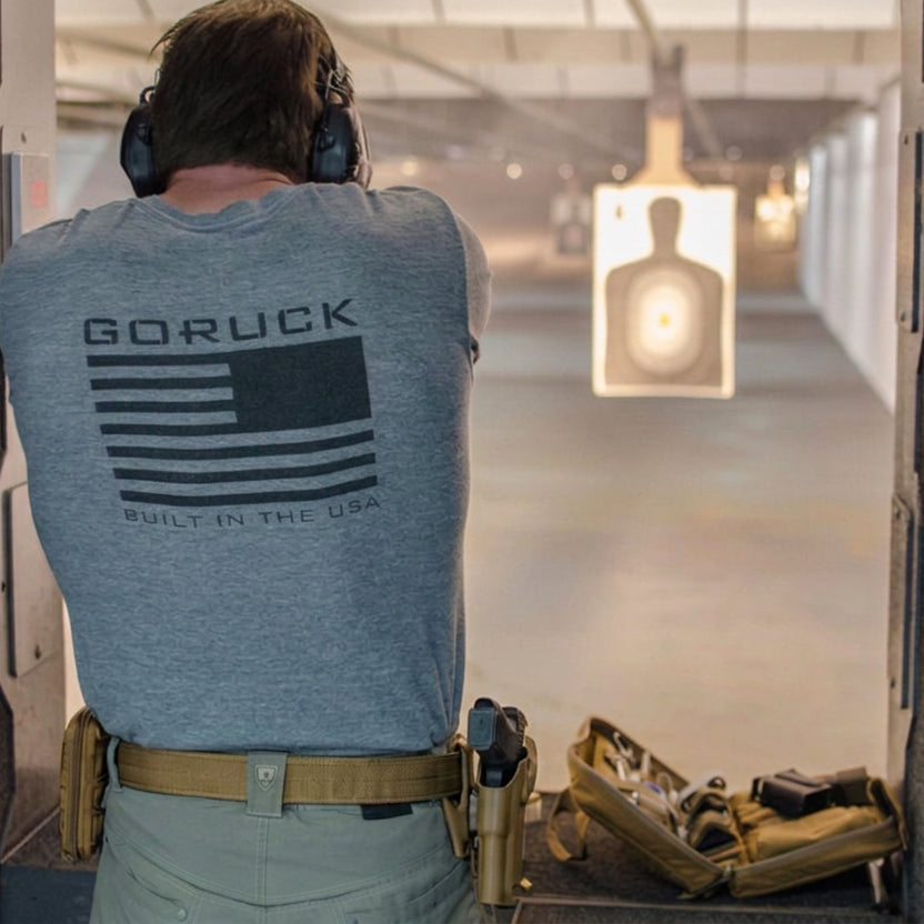 At an indoor shooting range, a person wearing ear protection and a 