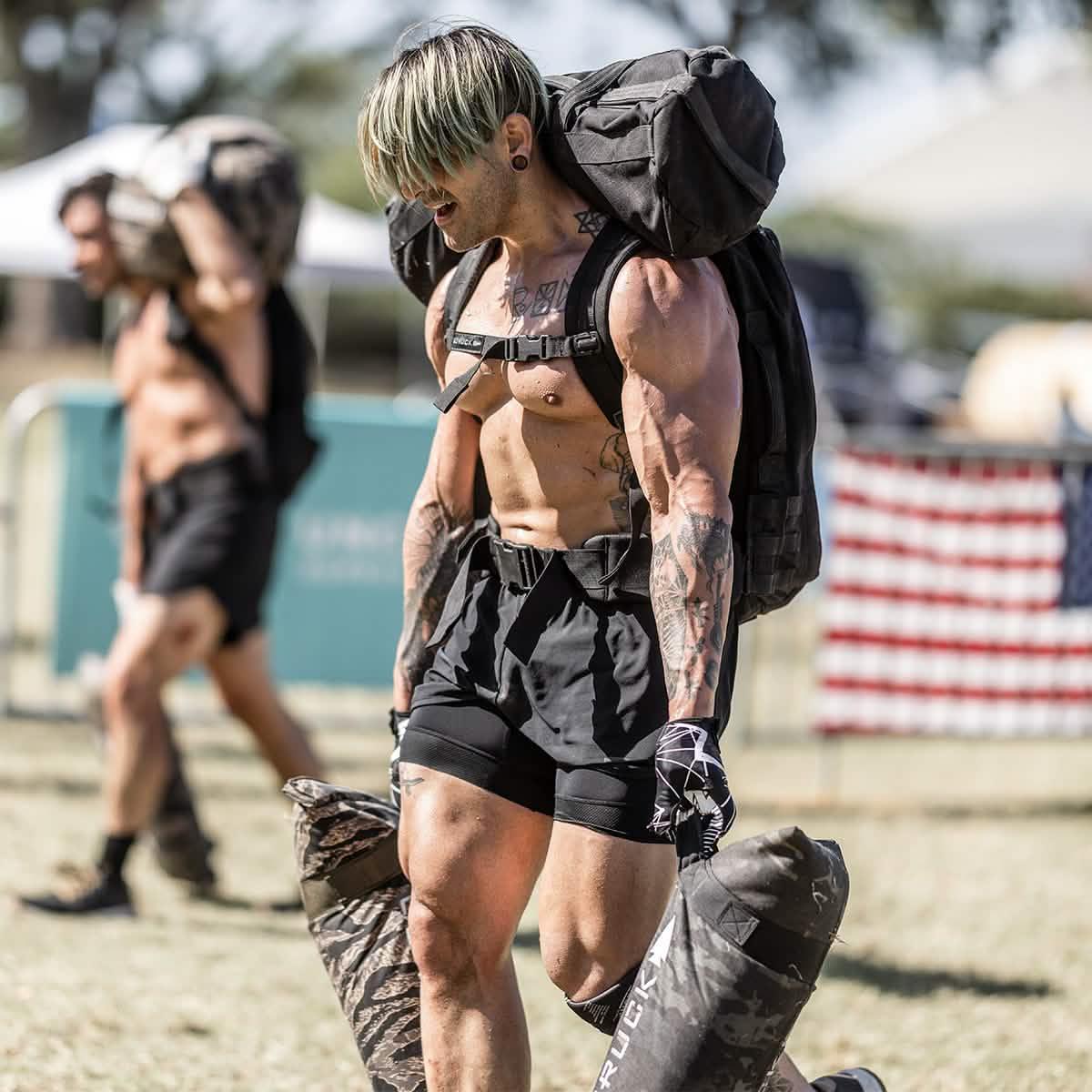Athlete in black GORUCK ranger panties carrying heavy ruck and sandbags outdoors