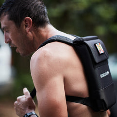 A man outdoors wearing the Ruck Plate Carrier 3.0 weighted backpack, with enhanced lumbar support visible on the strap.