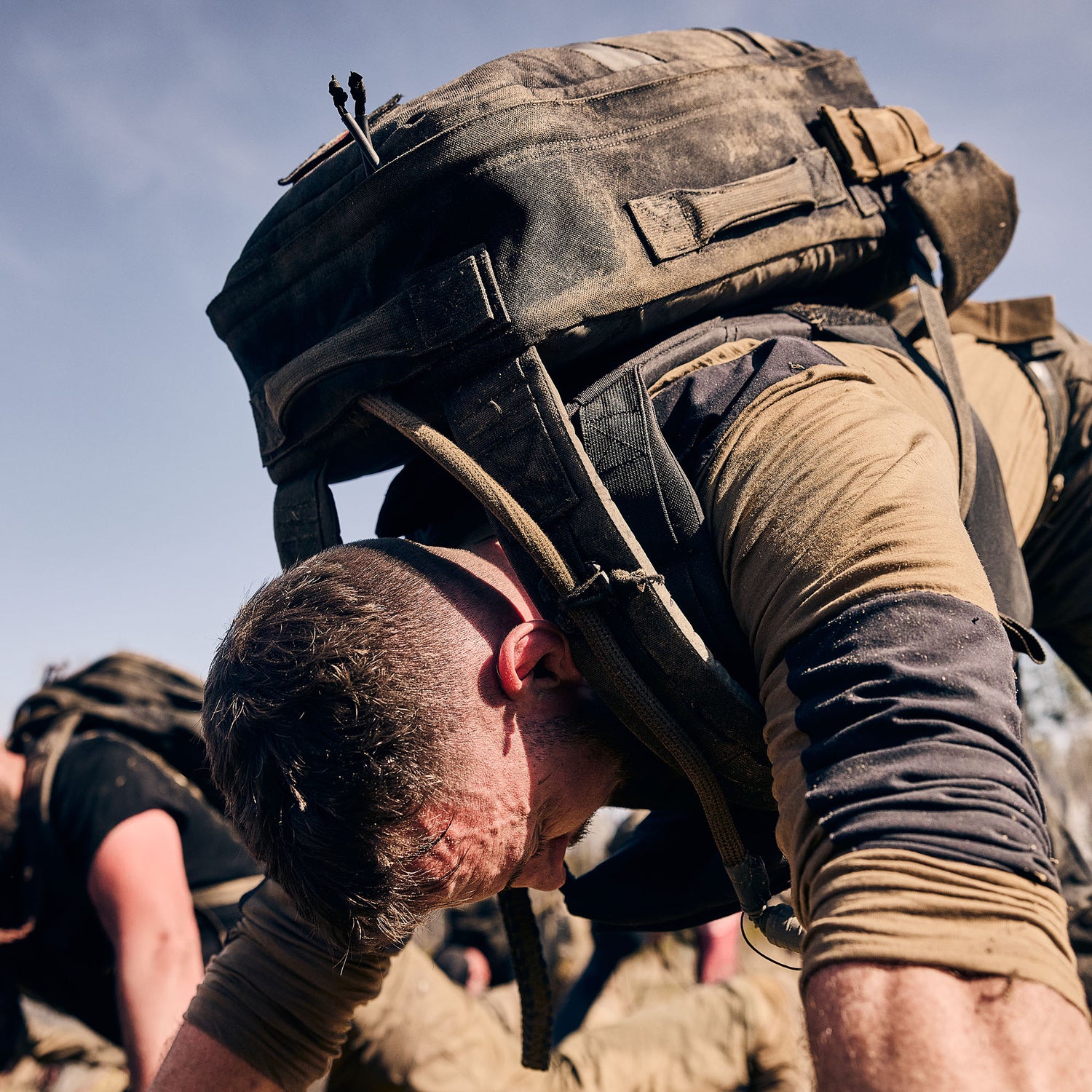 A man wearing the Rucker 5.0 performs intense outdoor exercise, leaning forward on his hands for lumbar support.