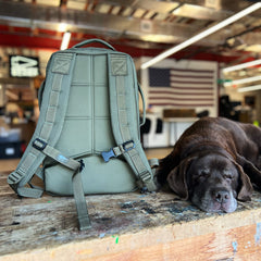 A Rucker 5.0 and a sleeping brown dog rest on a wooden table in a workshop, with an American flag in the background.